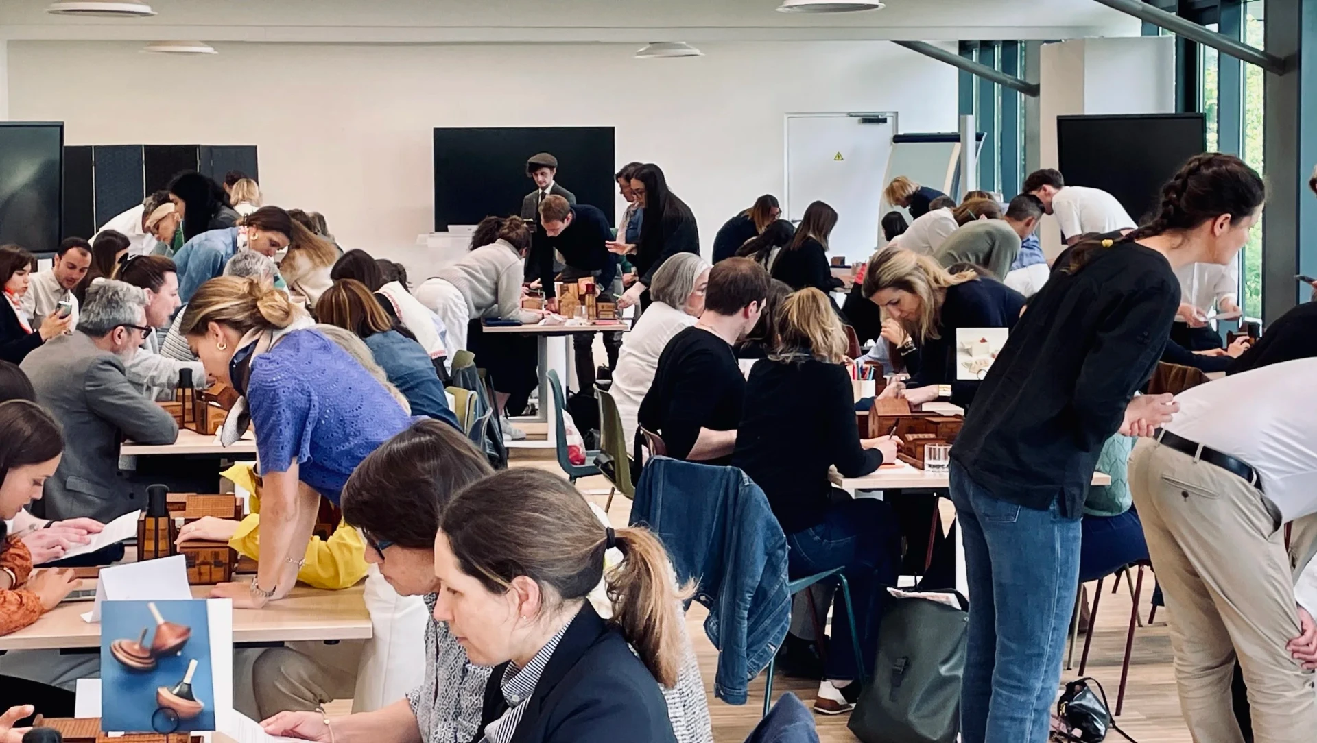 Sala corporativa com dezenas de colaboradores a resolver caixas de puzzle em equipa